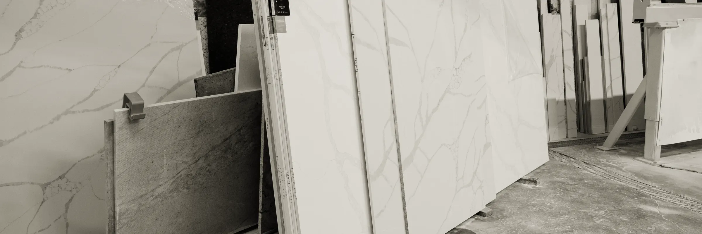 Engineered stone and marble slabs leaning in rows on the floor of a fabrication factory